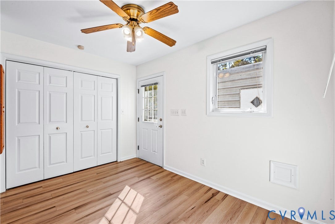 20040 Paradise Lane, Ruther Glen, VA 22546 Wood-finish flooring, white four-panel bi-fold closet doors, brass-finish ceiling fan with integrated lighting, single-pane window, and white exterior entry door with glass pane