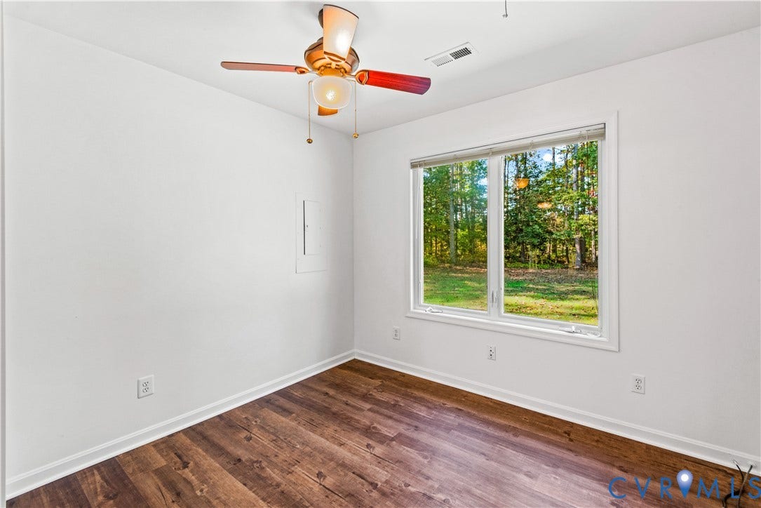 20040 Paradise Lane, Ruther Glen, VA 22546 Wood-finish flooring, multi-light ceiling fan, and a large window with woodland backdrop