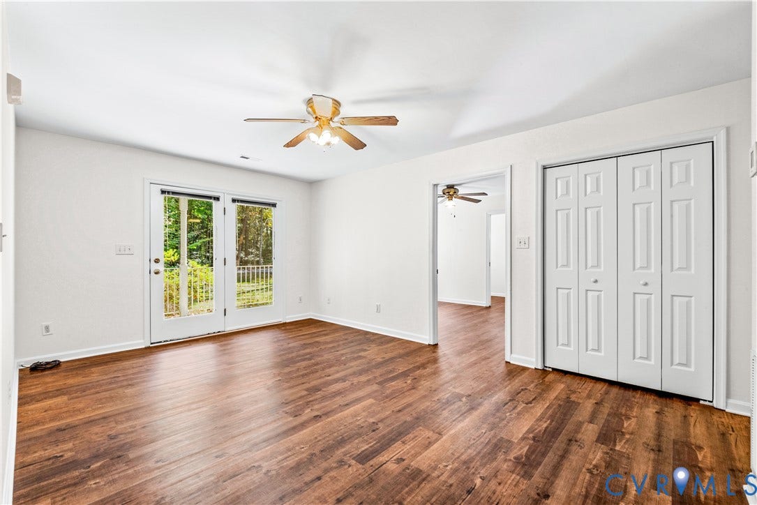 20040 Paradise Lane, Ruther Glen, VA 22546 Room featuring wood-finish flooring, dual-panel closet doors, and glass-paned double doors with integrated overhead lighting and ceiling fan