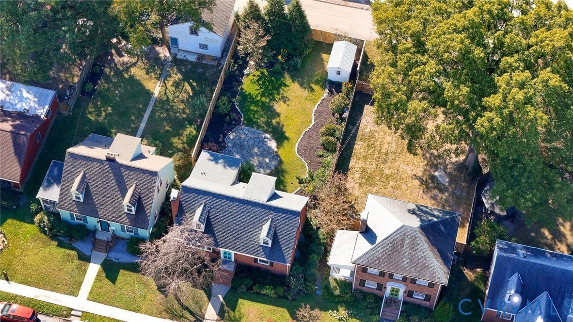 5028 Devonshire Road, Richmond, VA 23225 Expansive backyard featuring a fenced perimeter, stone-paver patio, manicured lawn, established shade trees, and a detached storage structure