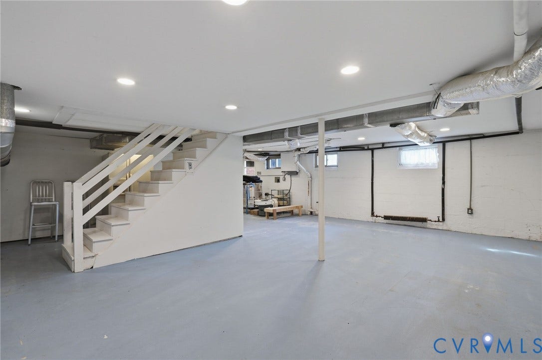 5028 Devonshire Road, Richmond, VA 23225 Open-concept area featuring recessed lighting, painted masonry walls, painted stairs with a wooden handrail, and coated concrete flooring