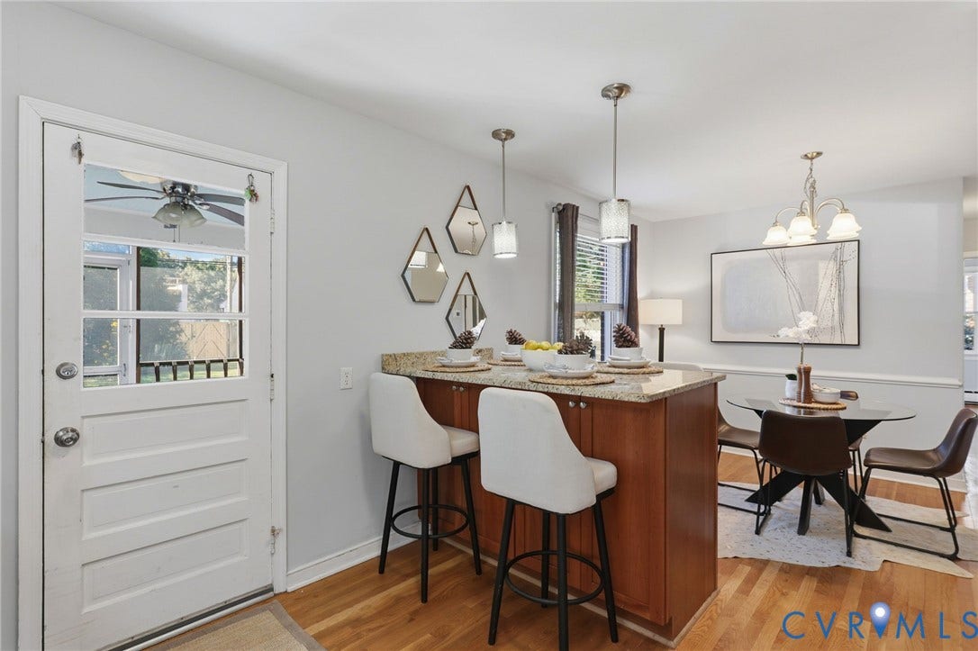 5028 Devonshire Road, Richmond, VA 23225 Wood-finish flooring, stone-surfaced kitchen island with built-in cabinetry, dual glass pendant lights, and decorative five-light chandelier