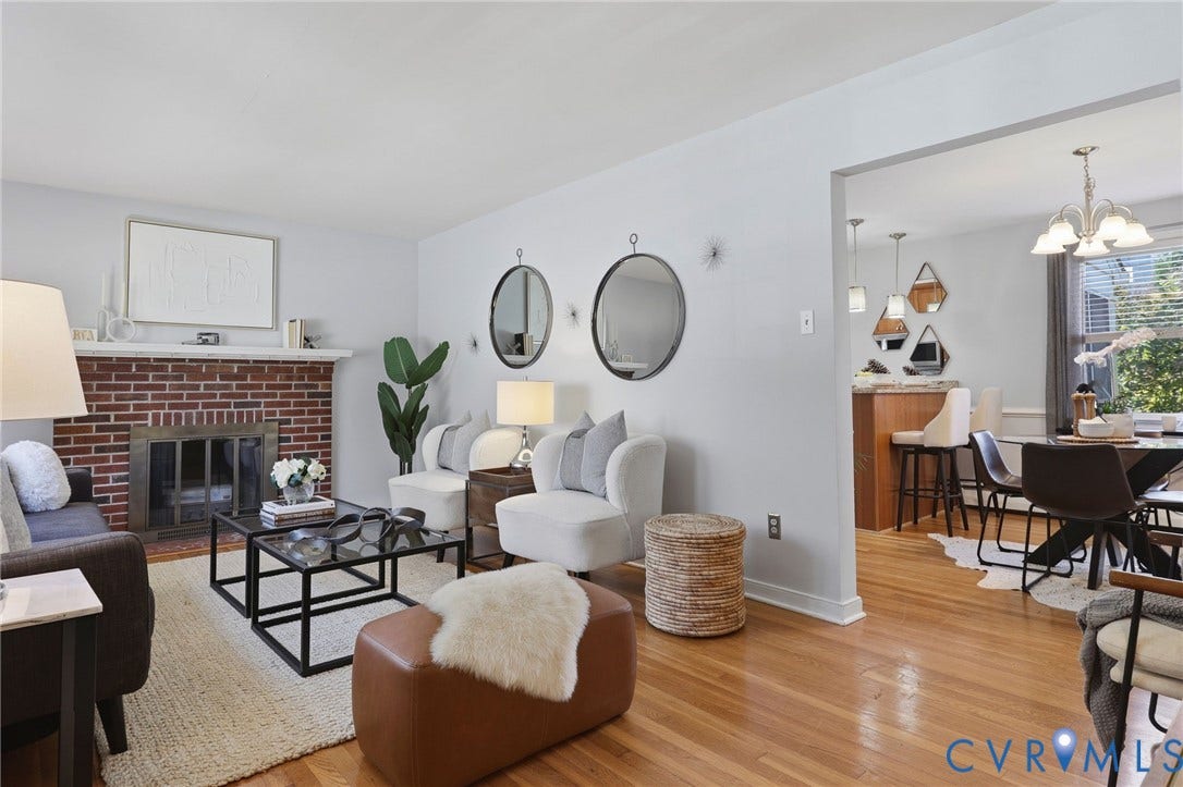 5028 Devonshire Road, Richmond, VA 23225 Living area featuring a red brick fireplace with a wood mantel, wood-finish flooring, and a multi-pendant dining light fixture