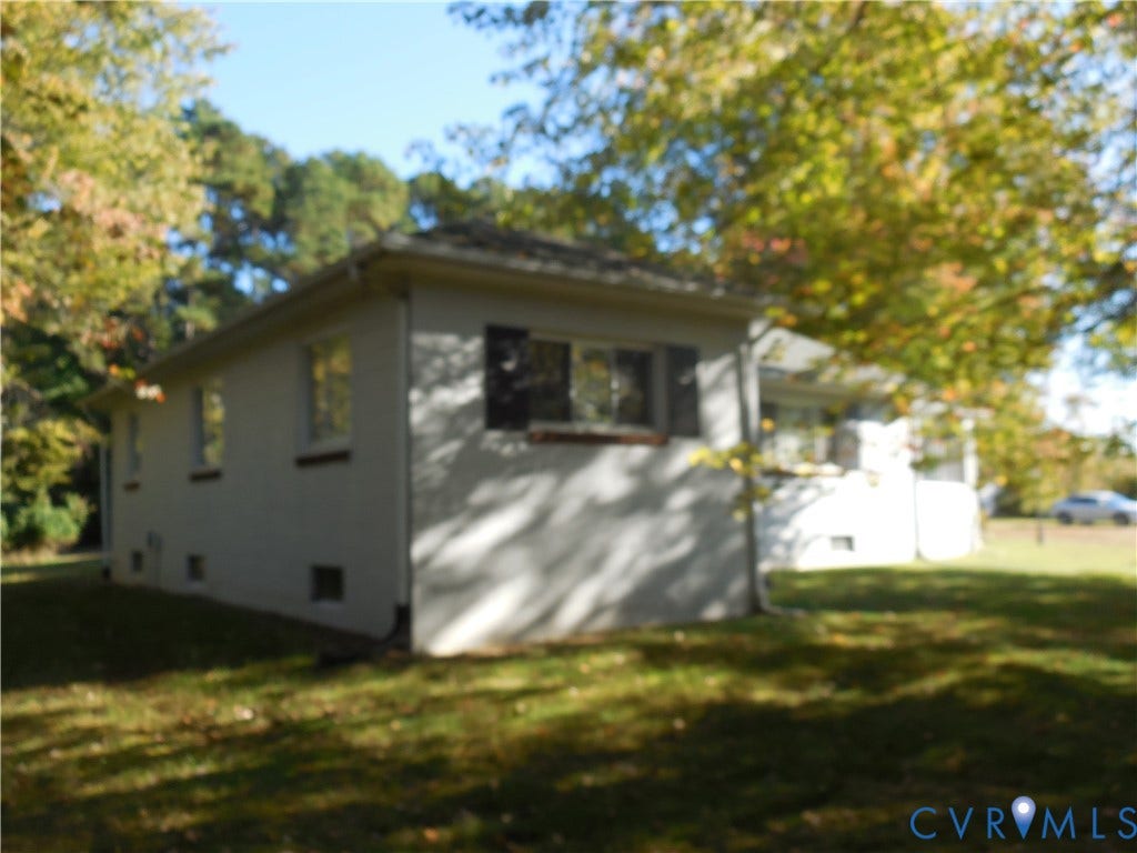 25 Bethany Church Road, Bumpass, VA 23024 Light-toned siding exterior featuring dark shutters, a hip roof, and surrounding mature trees