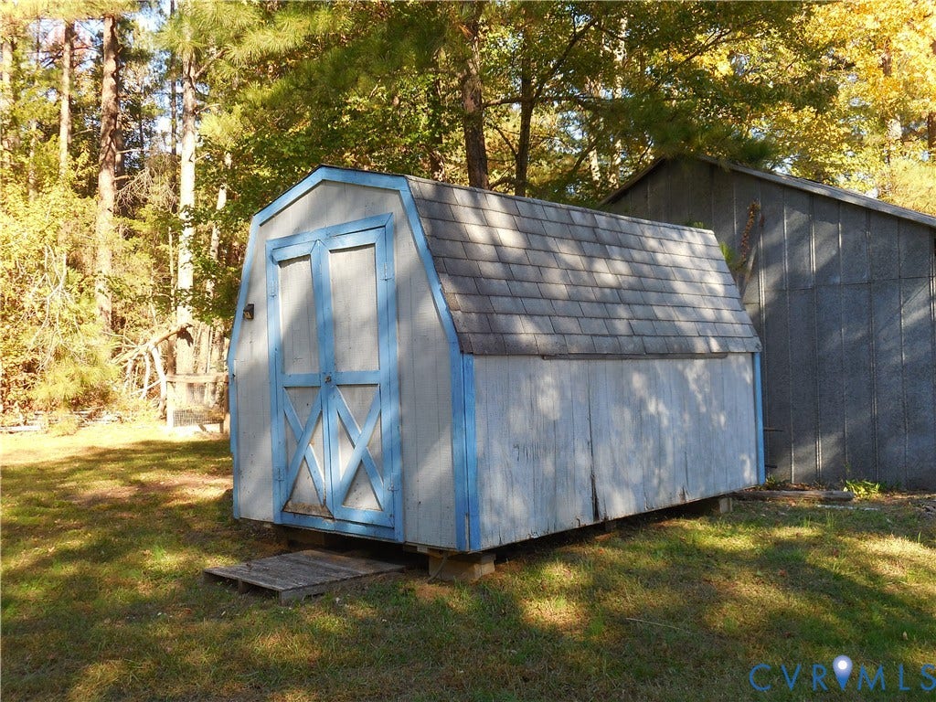 25 Bethany Church Road, Bumpass, VA 23024 Barn-style storage structure with dual swinging doors, shingled roofing, and wood-panel siding