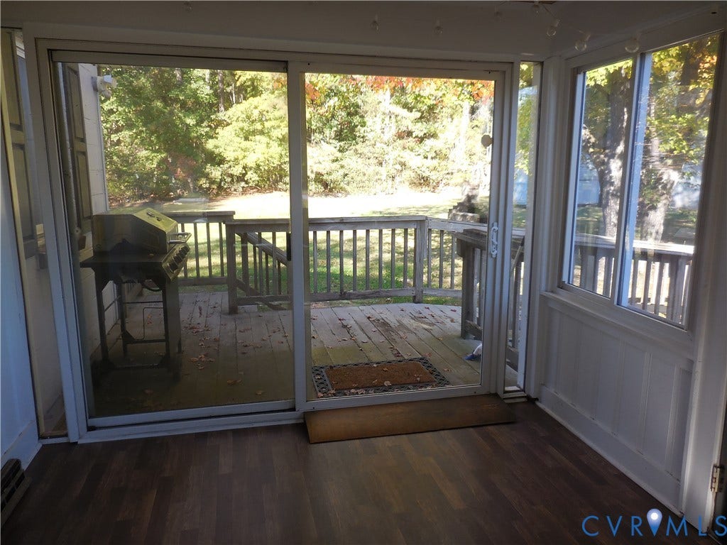 25 Bethany Church Road, Bumpass, VA 23024 Enclosed sunroom featuring wood-finish flooring, white paneling, expansive sliding glass doors, and an outdoor wood deck