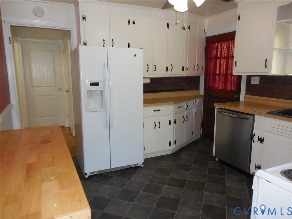 25 Bethany Church Road, Bumpass, VA 23024 Kitchen featuring white cabinetry with dark iron-finish hardware, solid-surface countertops, a brick backsplash, and checkerboard-patterned floor tile