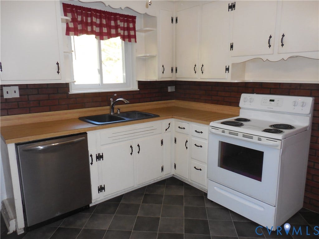 25 Bethany Church Road, Bumpass, VA 23024 Kitchen featuring white cabinetry, wood-finish countertops, brick backsplash, dual-basin sink, and tile flooring