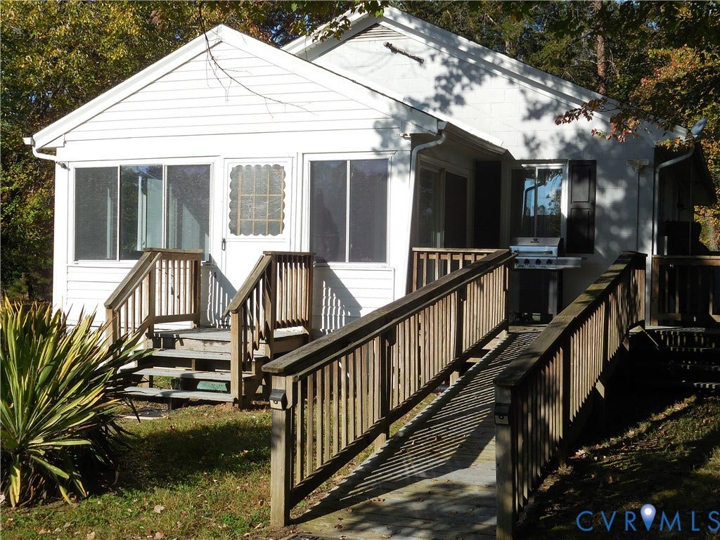 25 Bethany Church Road, Bumpass, VA 23024 White siding exterior featuring an enclosed sunroom, wooden deck, and wooden ramp with railings