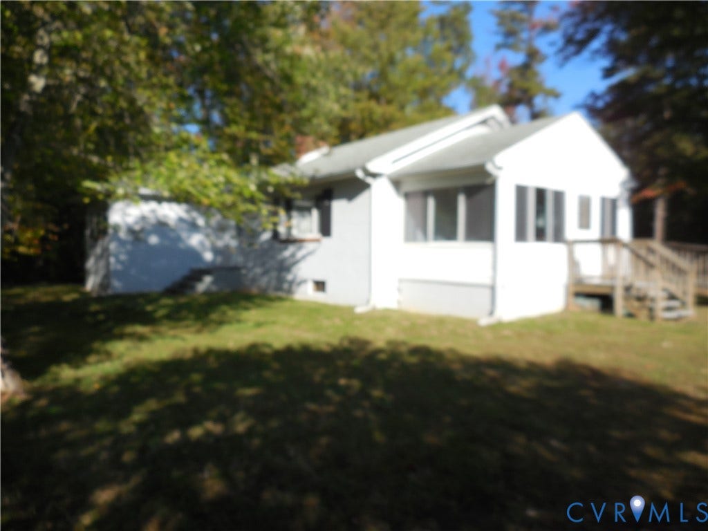 25 Bethany Church Road, Bumpass, VA 23024 Exterior featuring white siding, a gabled roof, an attached wooden deck, and a grass lawn