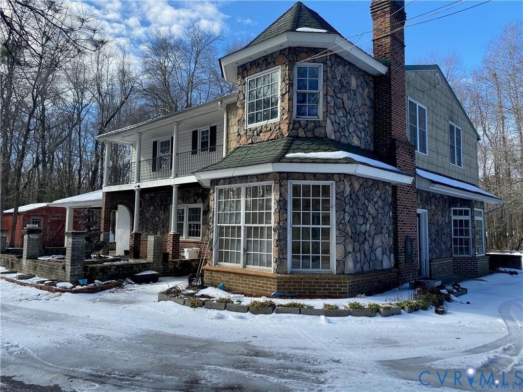 7010 Cogbill Road, Chesterfield, VA 23832 Multi-story stone and brick exterior featuring a turret, wraparound covered porch with metal railing, and a full-height masonry chimney