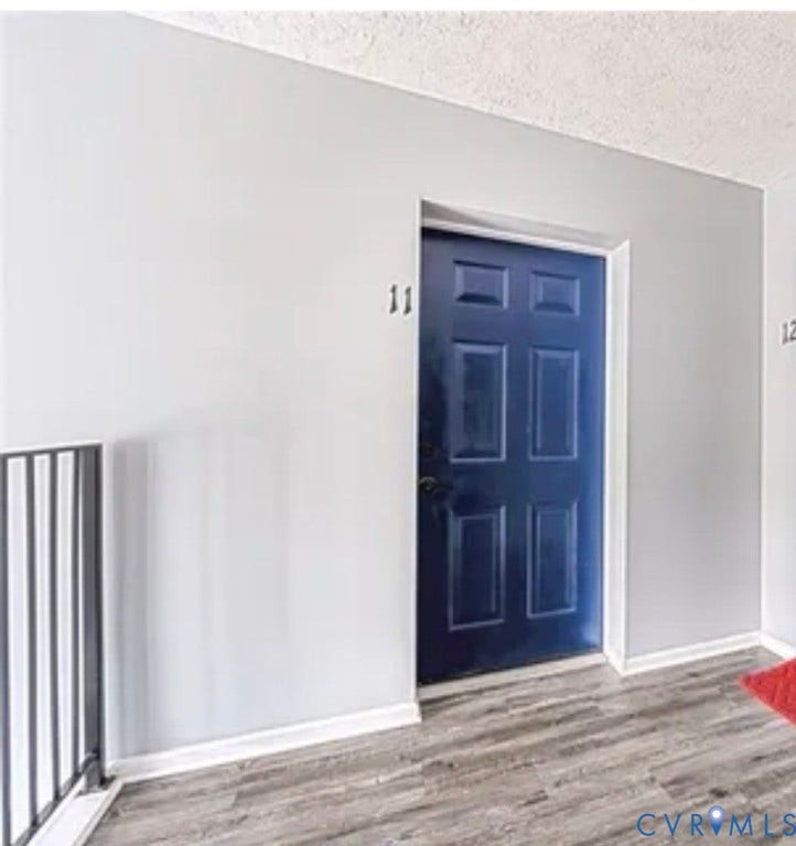 10211 Wolfe Manor Court, #711, Glen Allen, VA 23060 Six-panel navy blue entrance door featuring a metallic handle set, set within light-toned walls and wood-finish flooring with a metal railing