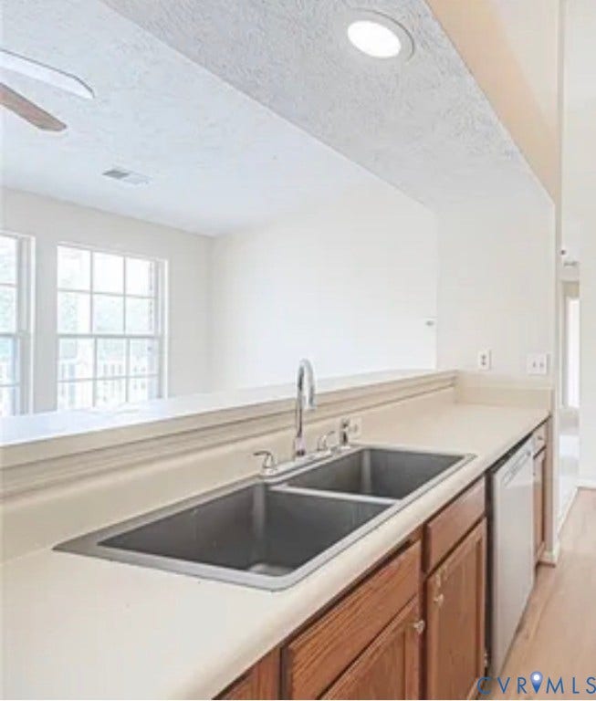10211 Wolfe Manor Court, #711, Glen Allen, VA 23060 Kitchen workspace featuring a dual-basin stainless steel sink, gooseneck faucet, light-toned solid surface countertops, and wood-finish cabinetry