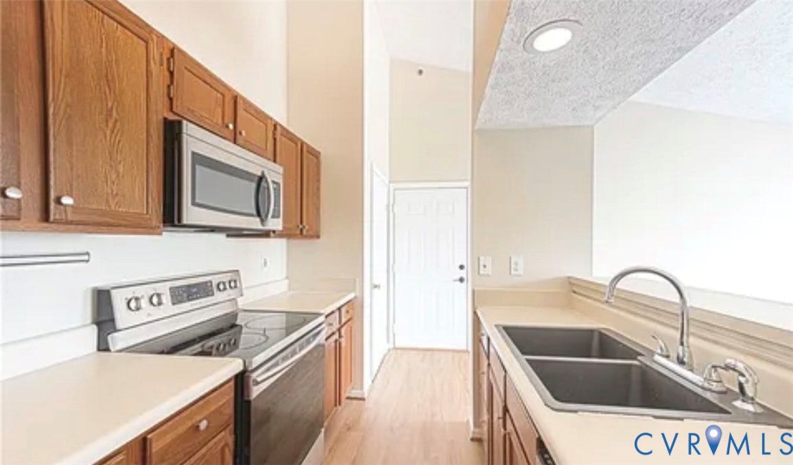 10211 Wolfe Manor Court, #711, Glen Allen, VA 23060 Kitchen featuring wooden cabinetry, stainless steel microwave and oven, high ceilings, wood-finish flooring, and a double-basin sink