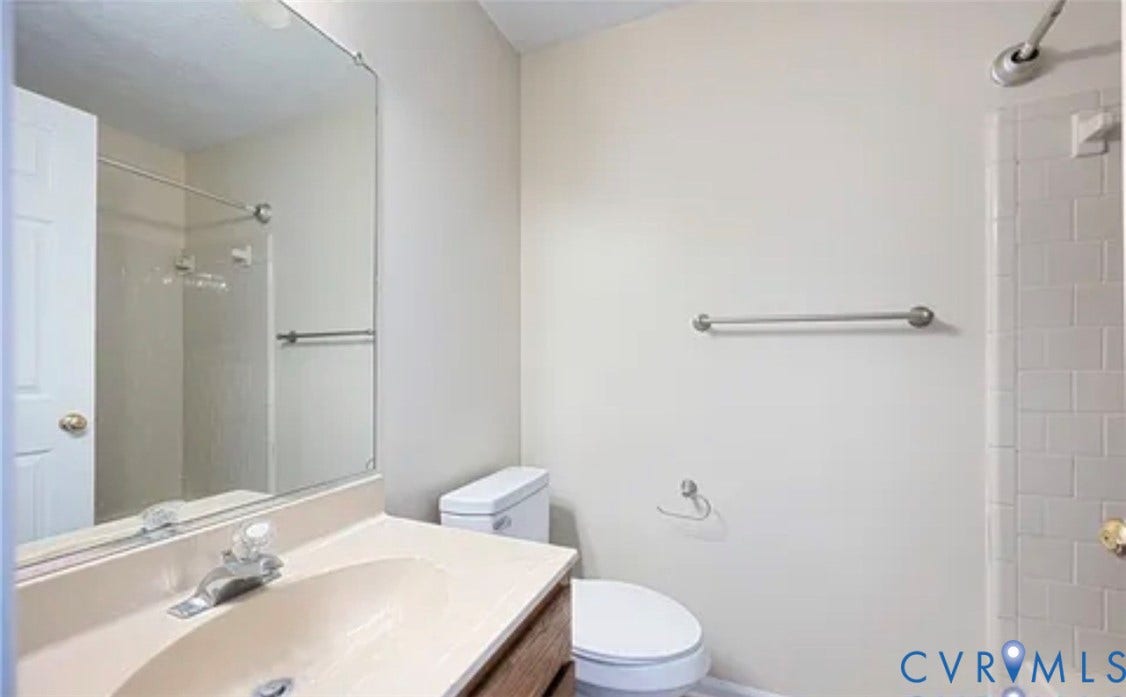 10211 Wolfe Manor Court, #711, Glen Allen, VA 23060 Bathroom featuring a vanity with integrated sink, large wall-mounted mirror, ceramic tile shower surround, and brushed nickel hardware