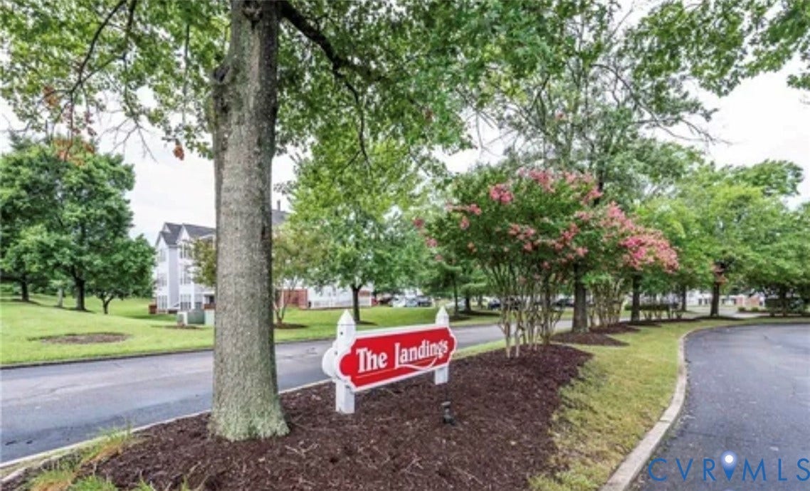 10211 Wolfe Manor Court, #711, Glen Allen, VA 23060 Landscaped grounds featuring mature trees, flowering shrubs, dark mulch beds, and paved roadways