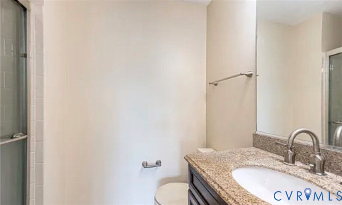 10211 Wolfe Manor Court, #711, Glen Allen, VA 23060 Bathroom featuring a stone-surface vanity with an integrated basin, brushed metal faucet, large wall-mounted mirror, and glass-enclosed shower