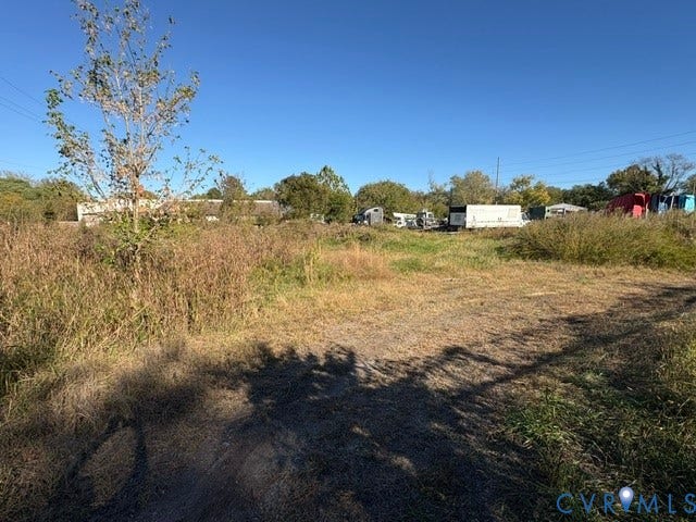 1143 McKenzie Street, Petersburg, VA 23803 Expansive open lot featuring natural vegetation, mature trees, and a dirt access path