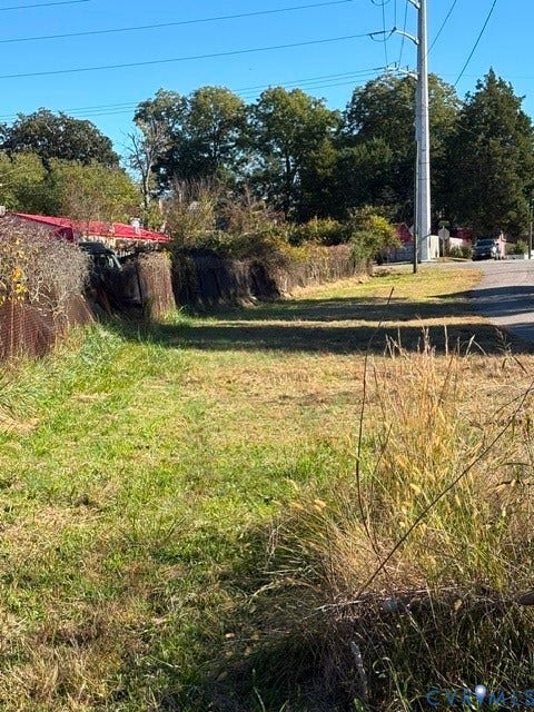 1143 McKenzie Street, Petersburg, VA 23803 Cleared parcel featuring native grasses, mature perimeter trees, and wire mesh fencing