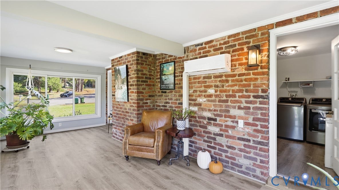 10010 Cheyenne Court, Richmond, VA 23235 Exposed brick accent wall featuring a wall-mounted ductless climate control unit, large-pane picture window, wood-finish flooring, and recessed ceiling lighting
