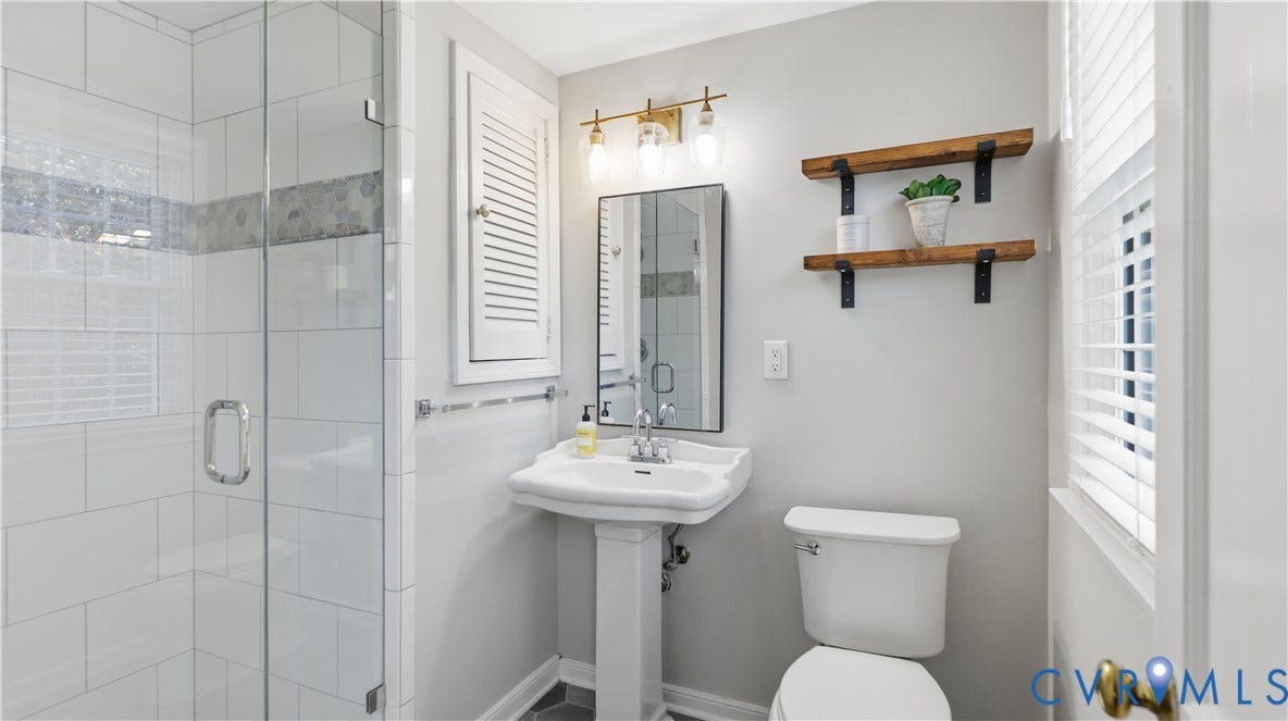 10010 Cheyenne Court, Richmond, VA 23235 Bathroom featuring a glass-enclosed shower with subway tile surround, white pedestal sink, three-light vanity fixture, and wall-mounted wooden shelving
