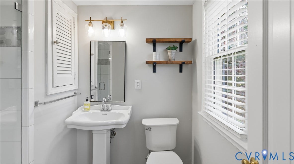 10010 Cheyenne Court, Richmond, VA 23235 Bathroom featuring a pedestal sink, wall-mounted three-light fixture, framed rectangular mirror, built-in louvered-door cabinet, and wall-mounted wood shelving