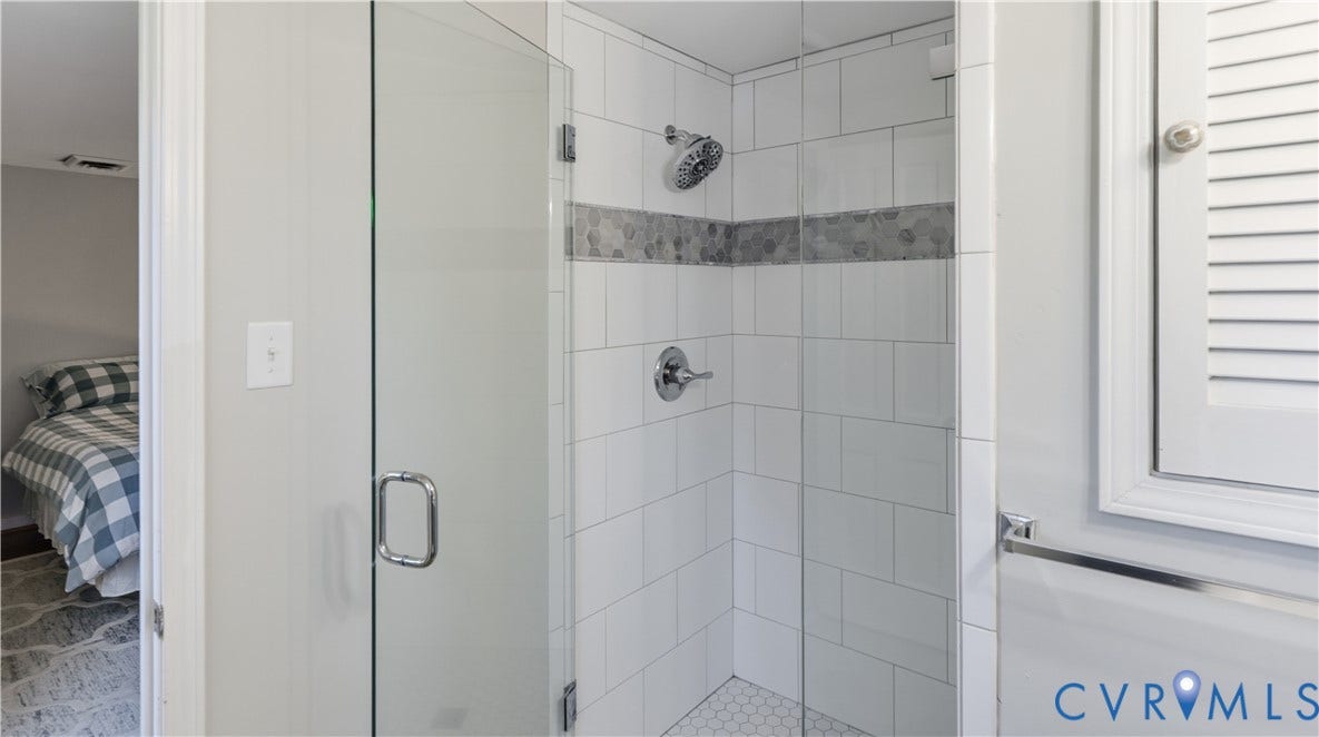 10010 Cheyenne Court, Richmond, VA 23235 Walk-in shower featuring a frameless glass door, white subway tile surround with a decorative mosaic inlay, chrome fixtures, and white hexagonal tile flooring