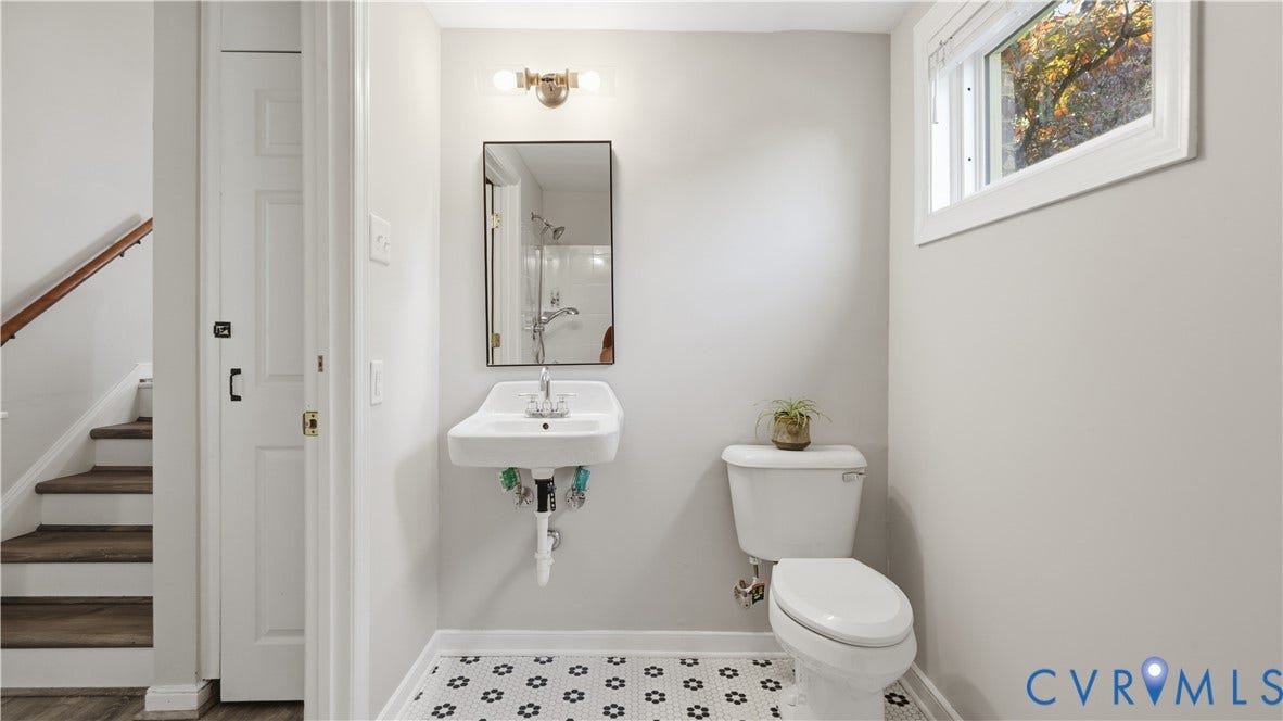 10010 Cheyenne Court, Richmond, VA 23235 Wall-mounted porcelain sink with chrome fixtures, rectangular mirror with metal frame, and geometric patterned floor tile