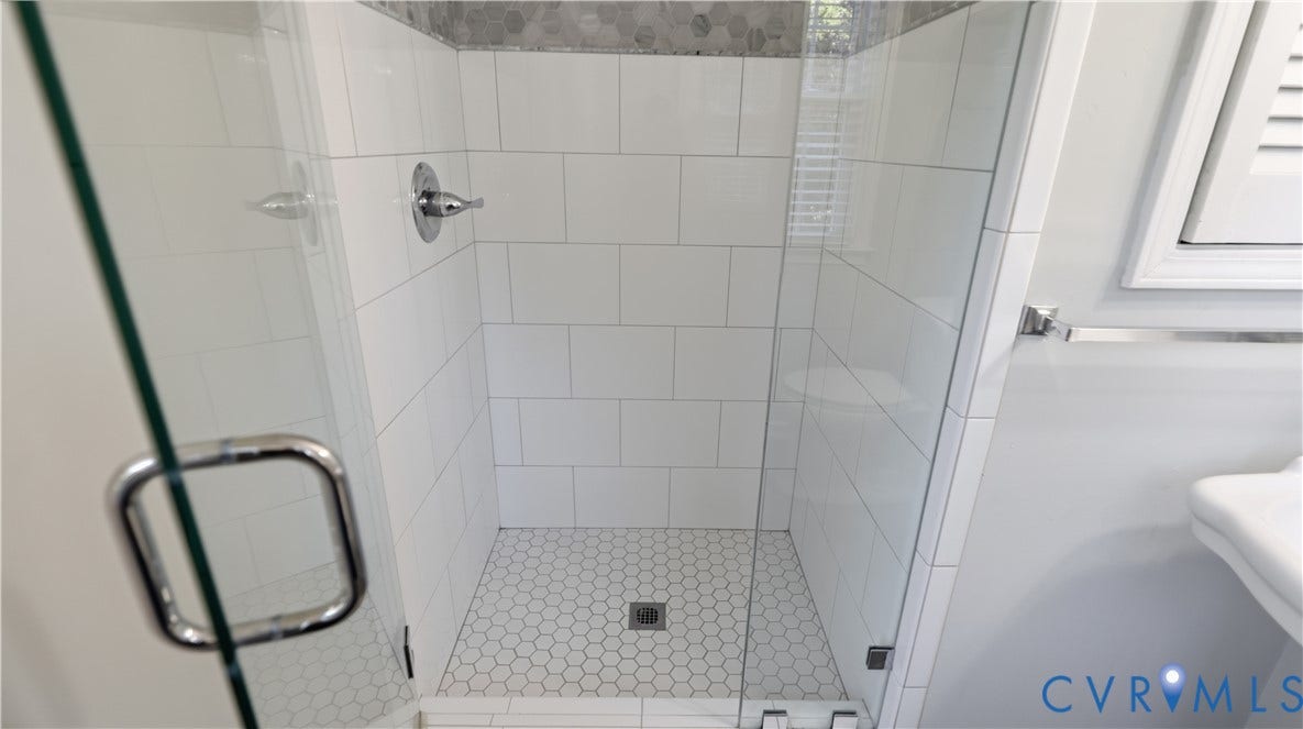 10010 Cheyenne Court, Richmond, VA 23235 Walk-in shower featuring white subway wall tile, hexagonal floor tile, chrome fixtures, and a frameless glass door