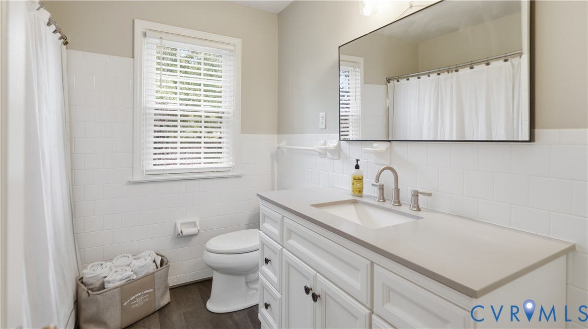 10010 Cheyenne Court, Richmond, VA 23235 Bathroom featuring a white shaker-style vanity with a solid surface countertop, undermount sink, framed wall mirror, and subway tile wainscoting