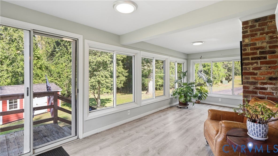 10010 Cheyenne Court, Richmond, VA 23235 Sunroom featuring light-toned wood-finish flooring, multiple expansive windows, a floor-to-ceiling brick chimney breast, and a sliding glass door providing access to a deck