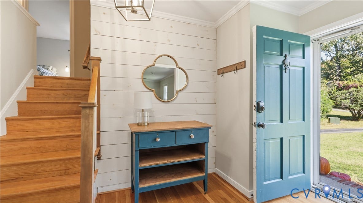 10010 Cheyenne Court, Richmond, VA 23235 Foyer featuring horizontal shiplap wall paneling, natural wood-finish staircase with matching handrail, six-panel teal entry door, and geometric metal pendant lighting