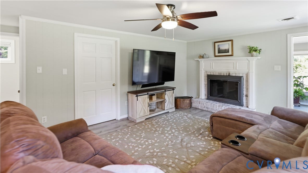 10010 Cheyenne Court, Richmond, VA 23235 Living room featuring a fireplace with a white mantel and painted brick hearth, wood-finish flooring, and a ceiling fan with integrated lighting