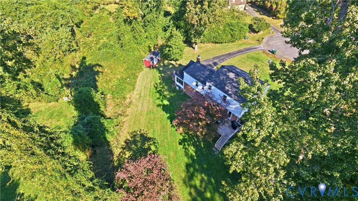 10010 Cheyenne Court, Richmond, VA 23235 Aerial perspective of a multi-story residence featuring an attached wooden deck, paved driveway, detached storage structure, and expansive grounds with mature trees