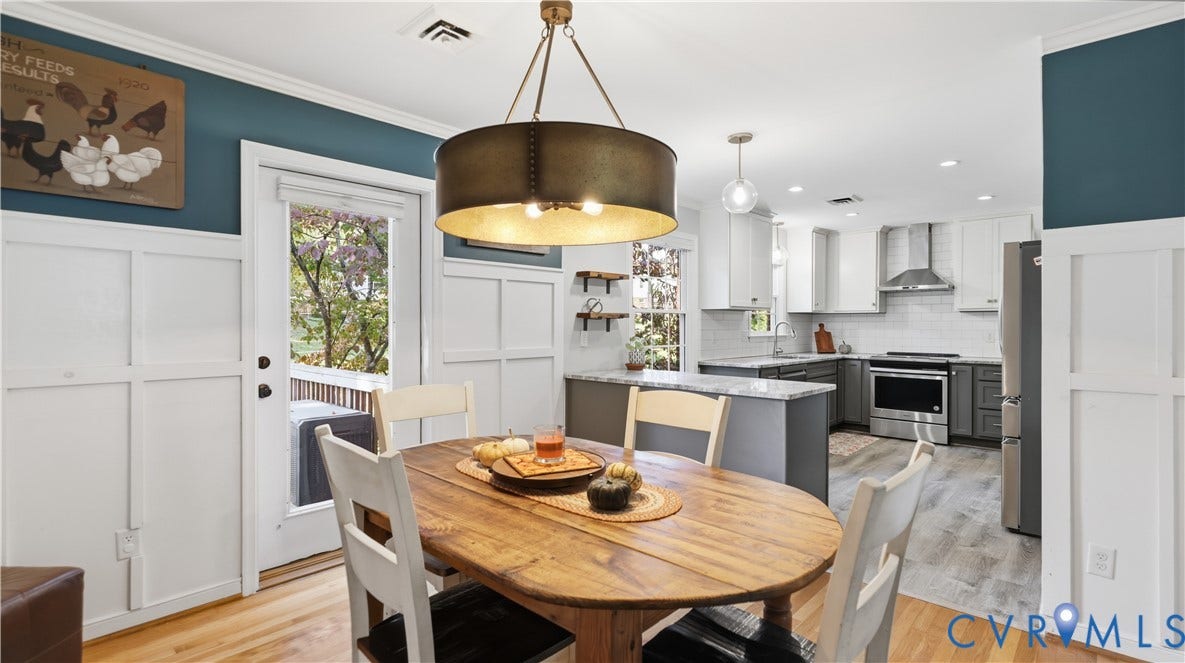 10010 Cheyenne Court, Richmond, VA 23235 Dining area featuring white board-and-batten wainscoting, an industrial-style drum pendant light, and wood-finish flooring, opening to a kitchen equipped with two-tone cabinetry and stainless steel appliances