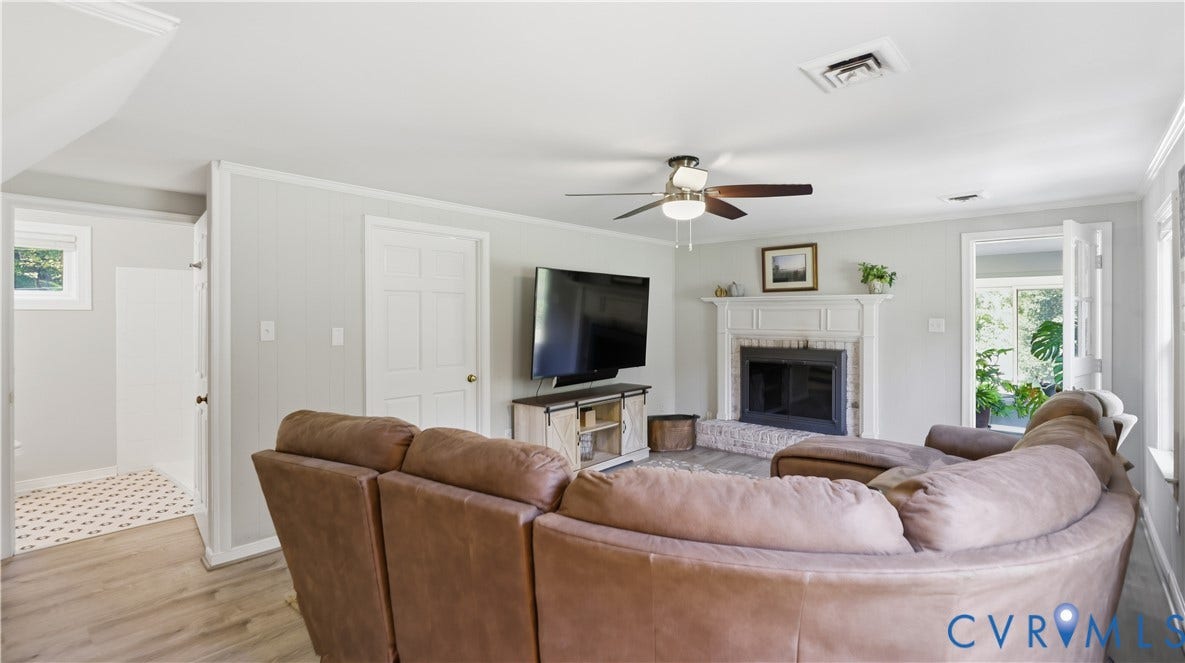 10010 Cheyenne Court, Richmond, VA 23235 Living area featuring a painted brick fireplace with a decorative mantel, ceiling fan with integrated lighting, wood-finish flooring, and crown molding