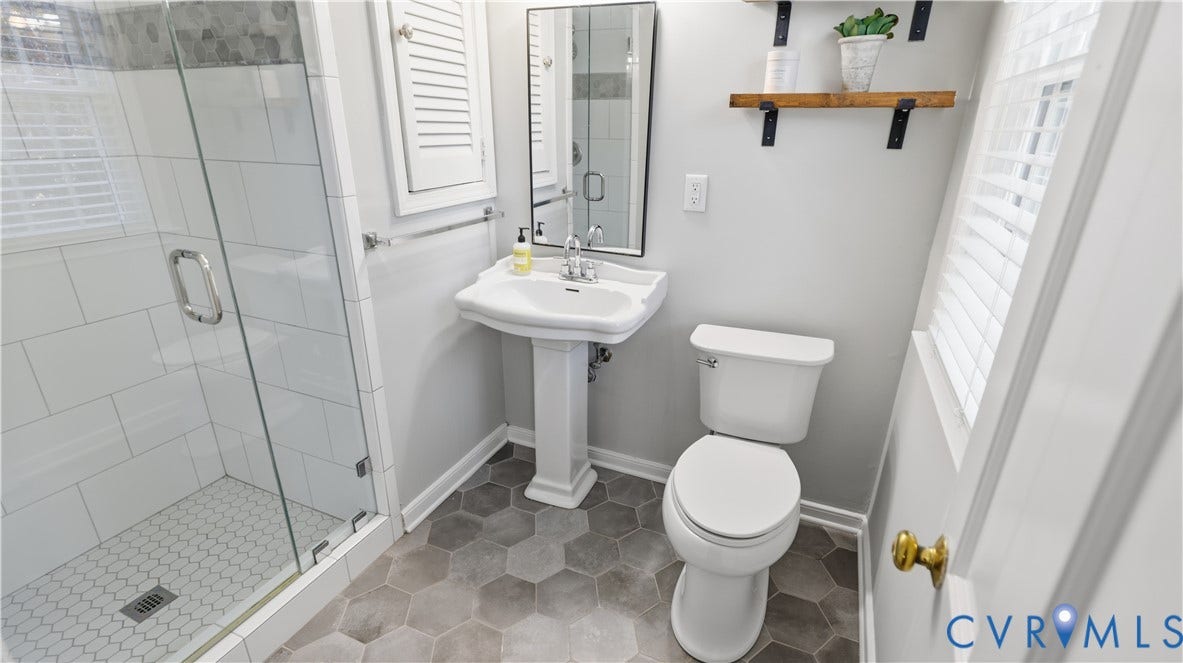 10010 Cheyenne Court, Richmond, VA 23235 Glass-enclosed shower with white subway tile surround, pedestal sink, hexagonal tile flooring, and wall-mounted shelving