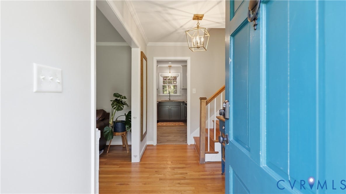 10010 Cheyenne Court, Richmond, VA 23235 Entryway featuring wood-finish flooring, a metal geometric pendant light, and a painted wooden front door with a metal knocker