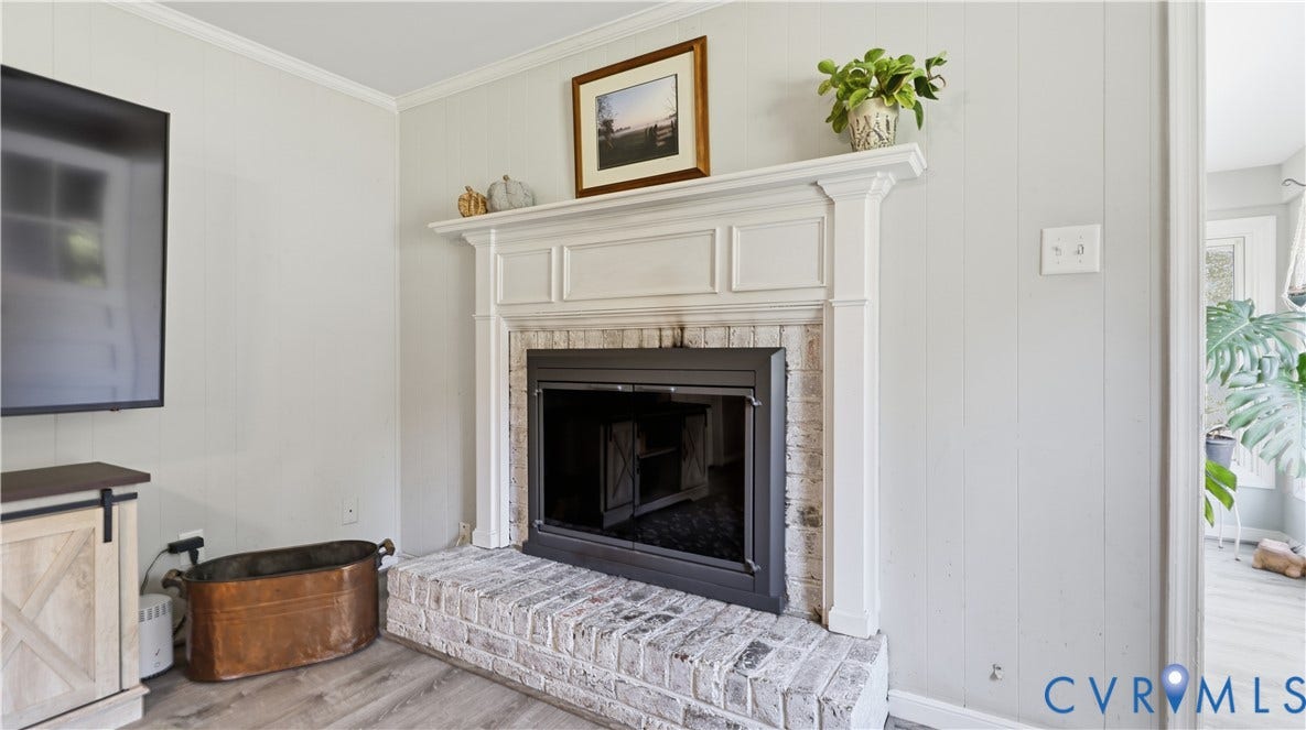 10010 Cheyenne Court, Richmond, VA 23235 Fireplace featuring a white-painted brick hearth, white custom mantel, wood-finish flooring, and vertical shiplap wall paneling