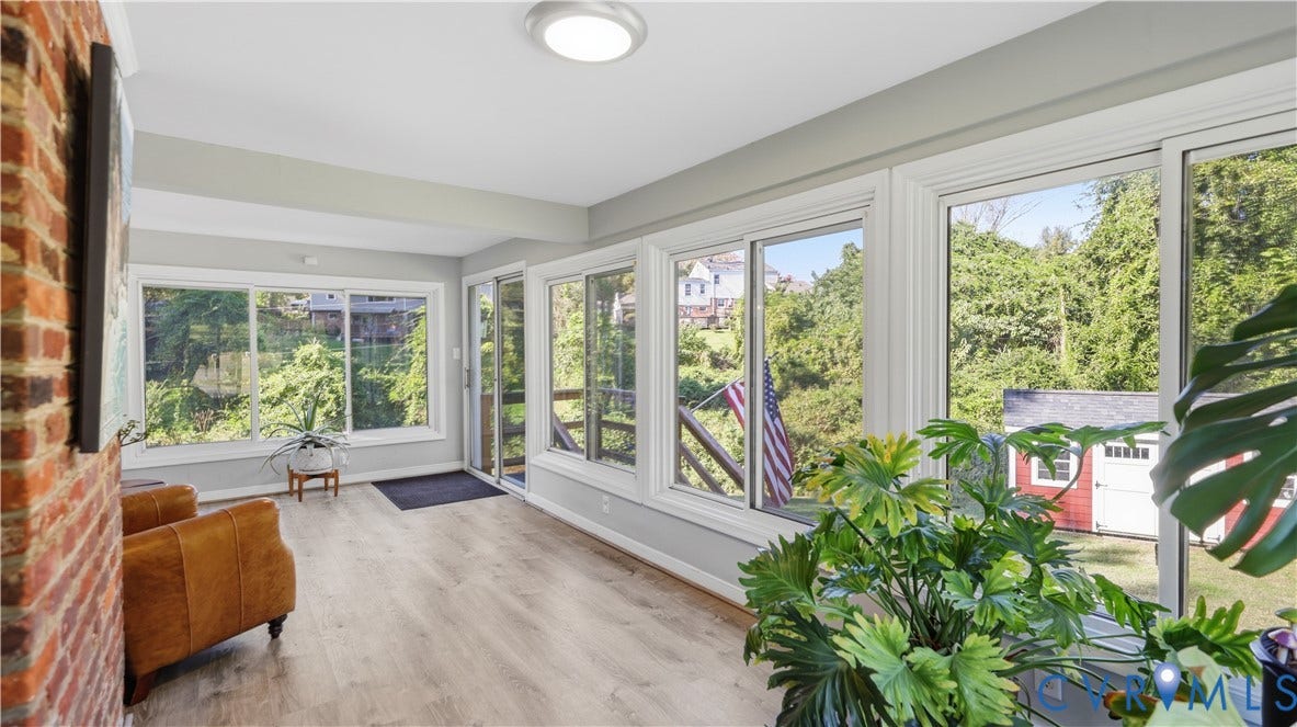 10010 Cheyenne Court, Richmond, VA 23235 Sunroom featuring wood-finish flooring, extensive sliding windows, and an exposed brick accent wall