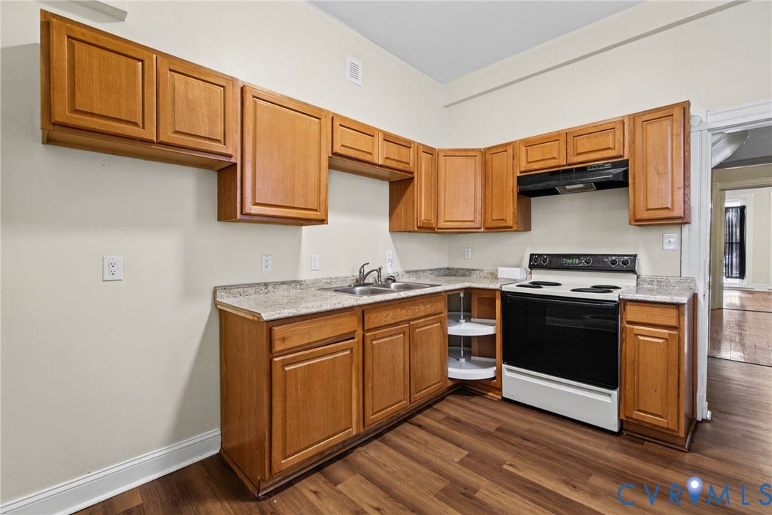 510 N 3rd Street, Jackson Ward, Richmond, VA 23219 Kitchen featuring natural wood cabinetry, stone-patterned laminate countertops, wood-finish flooring, a stainless steel dual-basin sink, and an integrated corner carousel cabinet