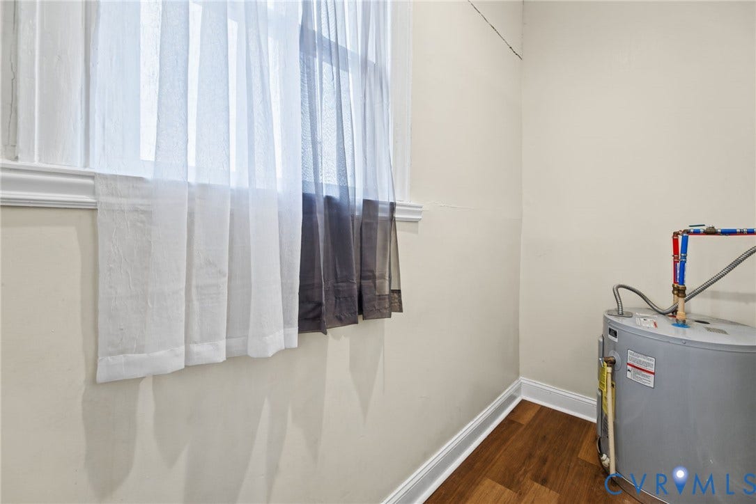 510 N 3rd Street, Jackson Ward, Richmond, VA 23219 Electric water heater with exposed plumbing connections, wood-finish flooring, and single-pane window with white trim