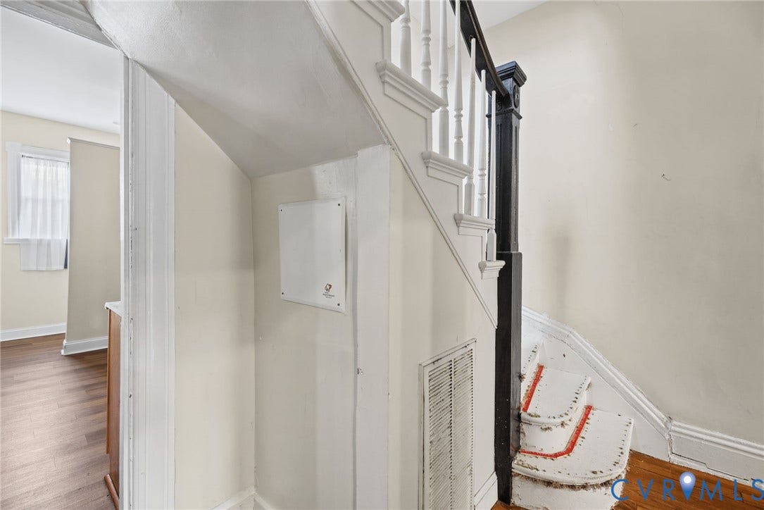 510 N 3rd Street, Jackson Ward, Richmond, VA 23219 Staircase featuring white balusters, a dark-toned square newel post, and wood-finish flooring