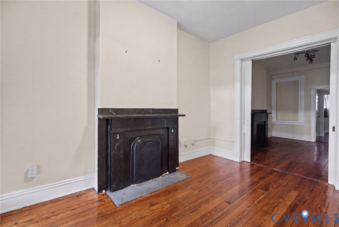 510 N 3rd Street, Jackson Ward, Richmond, VA 23219 Dark stone fireplace surround with a matching hearth, hardwood flooring, and wide door casing