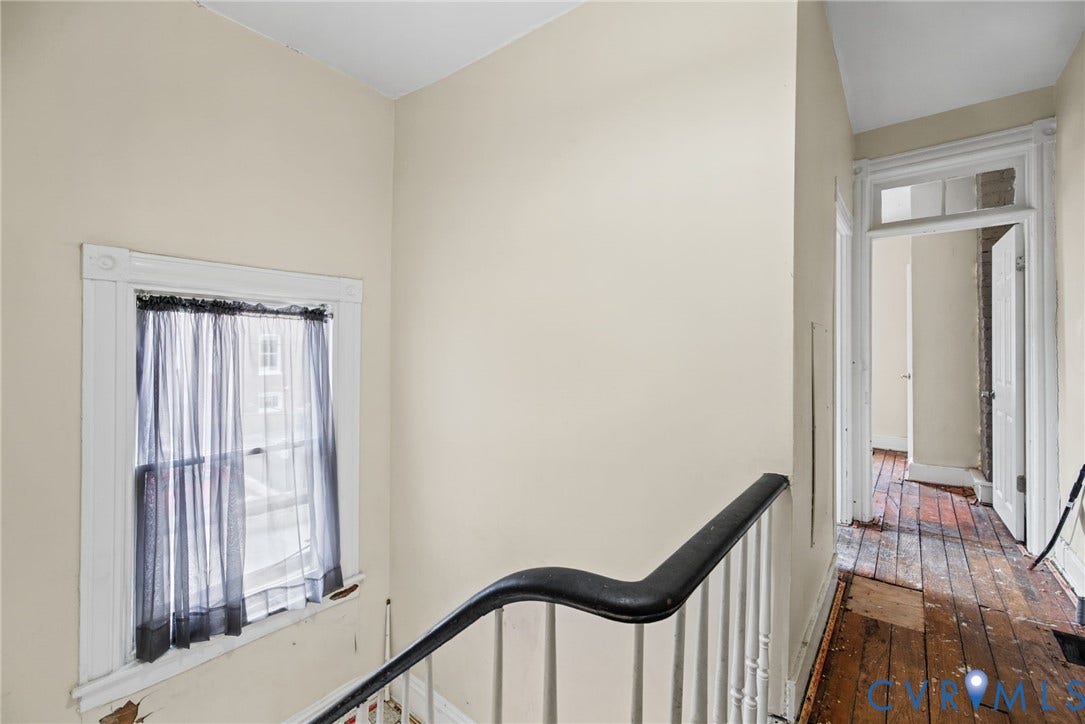 510 N 3rd Street, Jackson Ward, Richmond, VA 23219 Staircase featuring a painted wood handrail with balusters, wood-finish flooring, and window trim with a transomed door frame