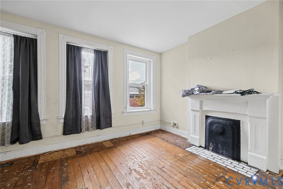 510 N 3rd Street, Jackson Ward, Richmond, VA 23219 Interior room featuring natural wood flooring, a white fireplace mantel, a black metal firebox insert, and multiple windows with white trim