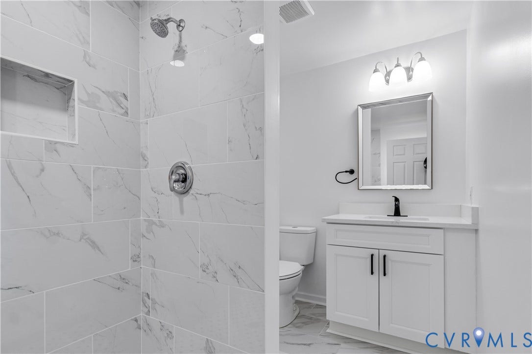 19614 Manson Church Road, Mc Kenney, VA 23872 Bathroom featuring a walk-in shower with large-format stone-patterned wall tiles and a built-in shower niche, a white vanity with integrated countertop, and matte black plumbing fixtures