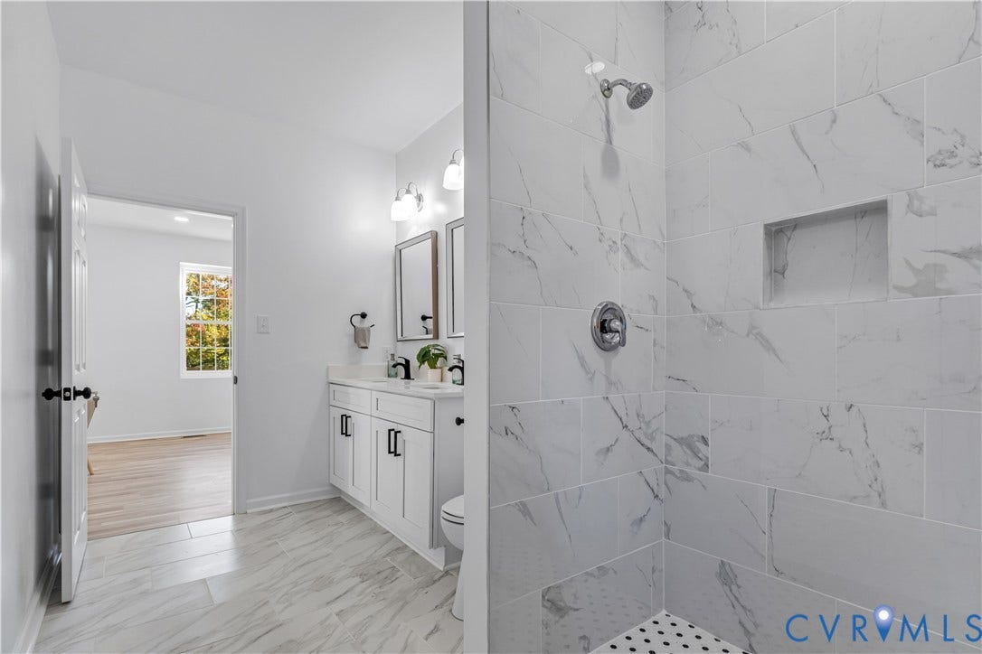 19614 Manson Church Road, Mc Kenney, VA 23872 Bathroom featuring a tiled shower with a built-in niche, dual-sink vanity with cabinet storage, and light-toned flooring