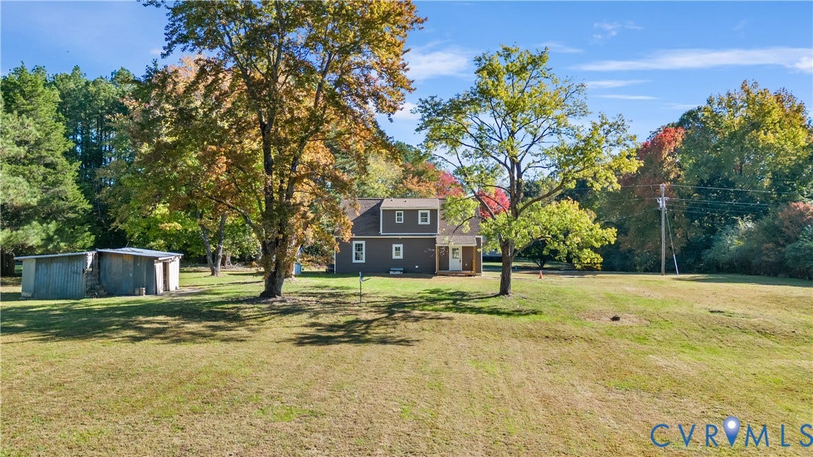 19614 Manson Church Road, Mc Kenney, VA 23872 Multi-level residence featuring dark wood siding, a covered entryway, an expansive lawn, mature trees, and a detached storage structure