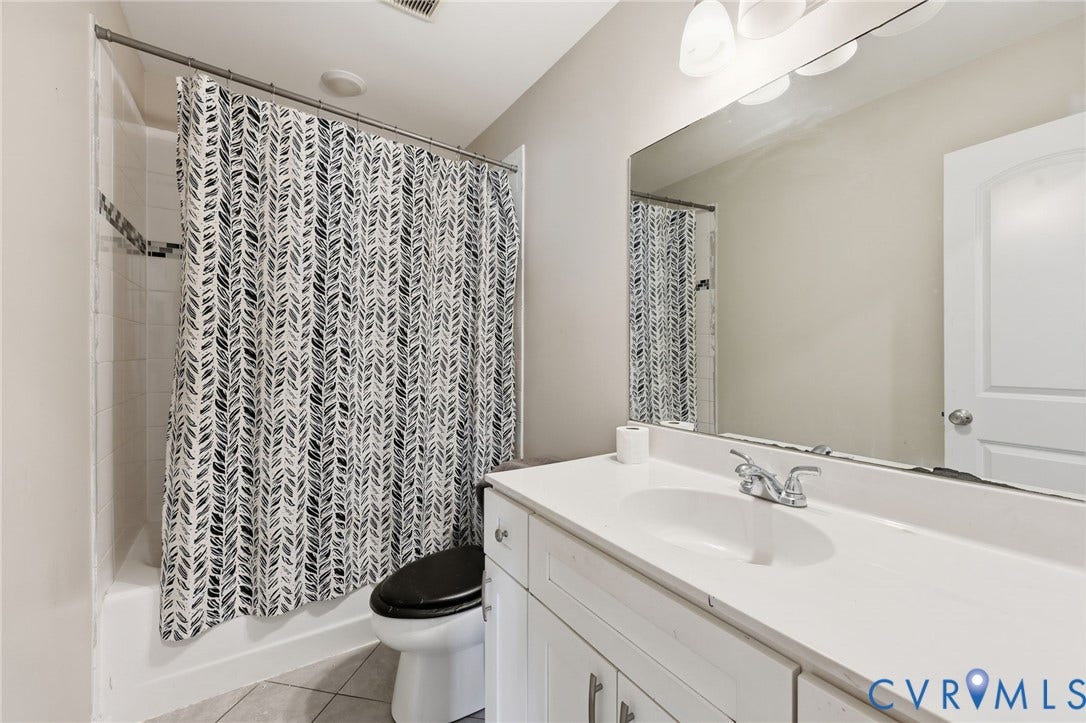 6614 Gills Gate Drive, Chesterfield, VA 23832 Full-width vanity with white cabinetry and integrated sink, large wall-mounted mirror, tub-shower combination with tile surround, and tile flooring